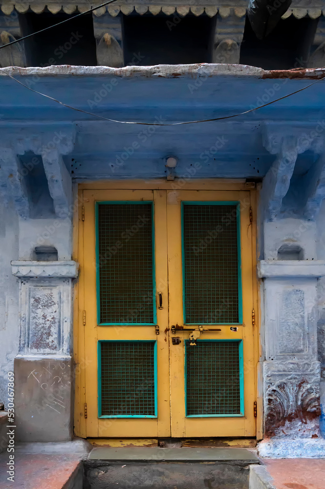 Traditional yellow door and blue coloured house of Jodhpur city, Rajsthan, India. Historically, Hindu Brahmins used to paint their houses in blue for being upper caste, the tradition follows.