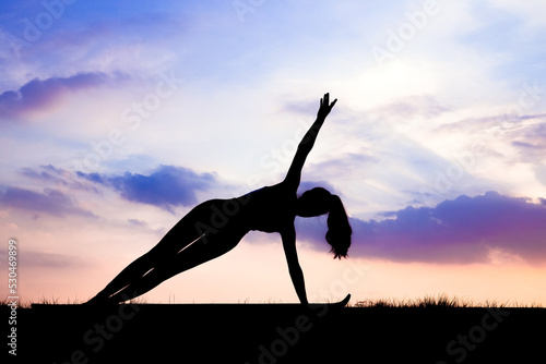 The slender girl is doing a yoga warm-up exercise outdoors
