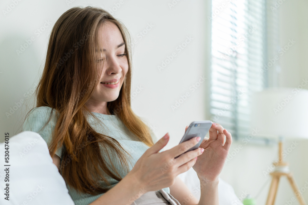 Young Caucasian woman use mobile phone chat on bed at home in morning. Young Caucasian woman use mobile phone chat on bed at home in morning.