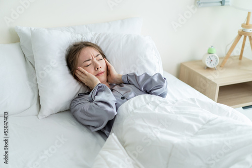 Caucasian beautiful frustrated girl in pajamas sleep on bed in morning.