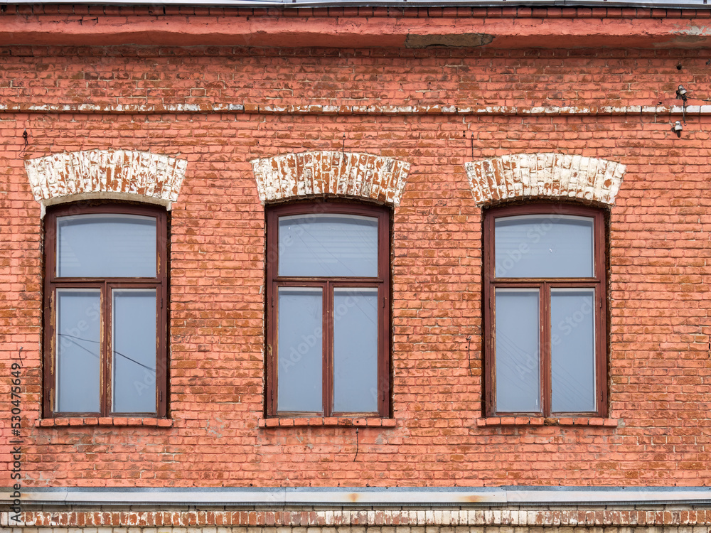 Three windows of the old mansion 19 century with brown bricks wall