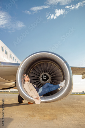 Cheerful woman resting in airplane engine at airfield