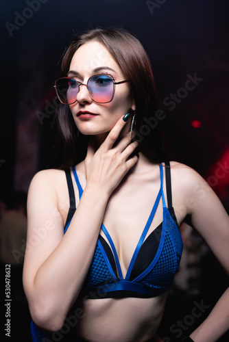 Portrait Beautiful girl in blue and black lingerie posing on the stage of a nightclub looking at the camera. Party concept