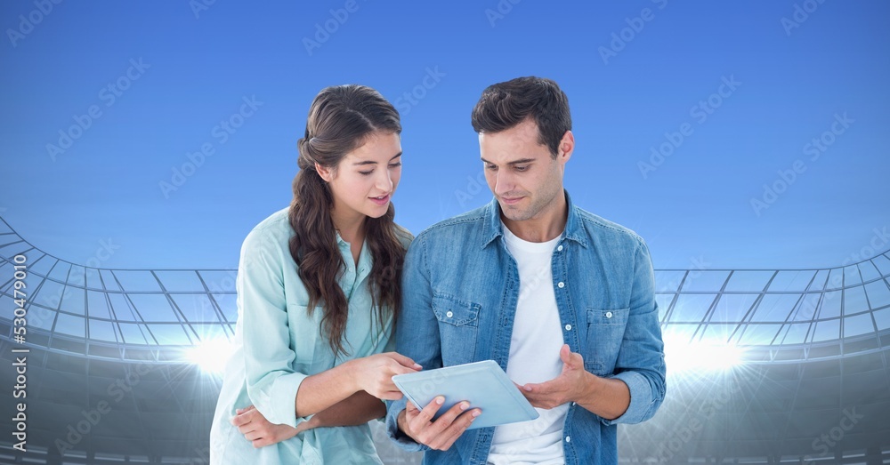 Obraz premium Composite image of caucasian couple using digital tablet against sports stadium with copy space