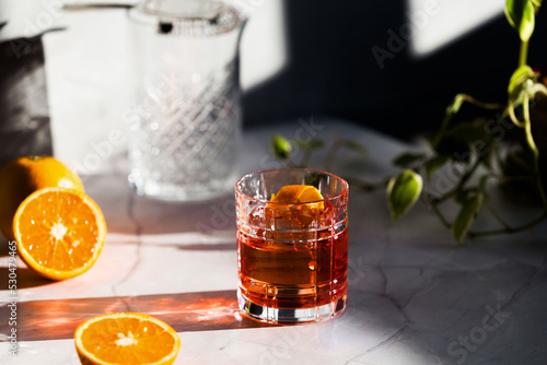 Bild auf Leinwand Photo of a Negroni cocktail glass with sun light and shadow and orange