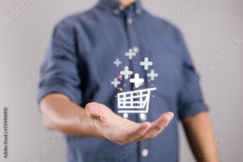 Businessman holding virtual shopping cart symbols with a plus sign to add or receive an order.