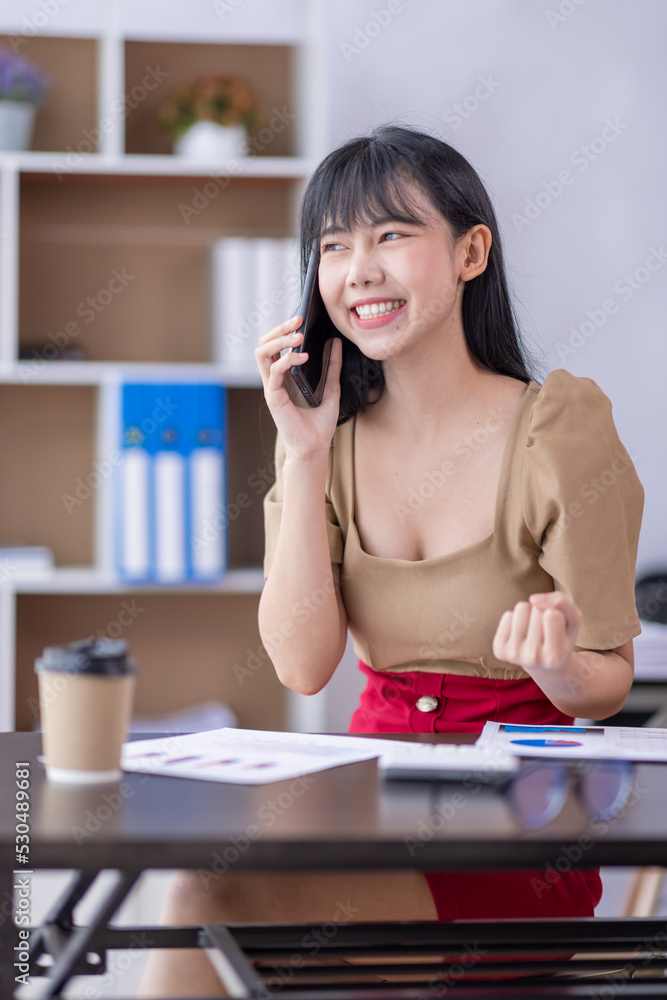 Excited happy Business Asian woman talking on phone and celebrating an online win, overjoyed young asian female screaming with joy and working at workplace Excited happy Business Asian woman talking on phone and celebrating an online win, overjoyed young asian female screaming with joy and working at workplace