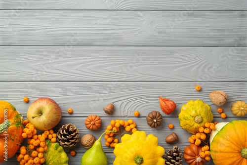 Autumn harvest concept. Top view photo of raw vegetables pumpkins pattypans apple pear walnuts rowan berries pine cones acorns and physalis on isolated grey wooden table background with copyspace photo