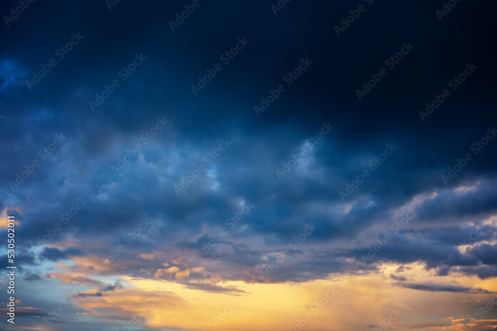 Abstract beautiful nature background, bright sunset sky with storm deep blue clouds
