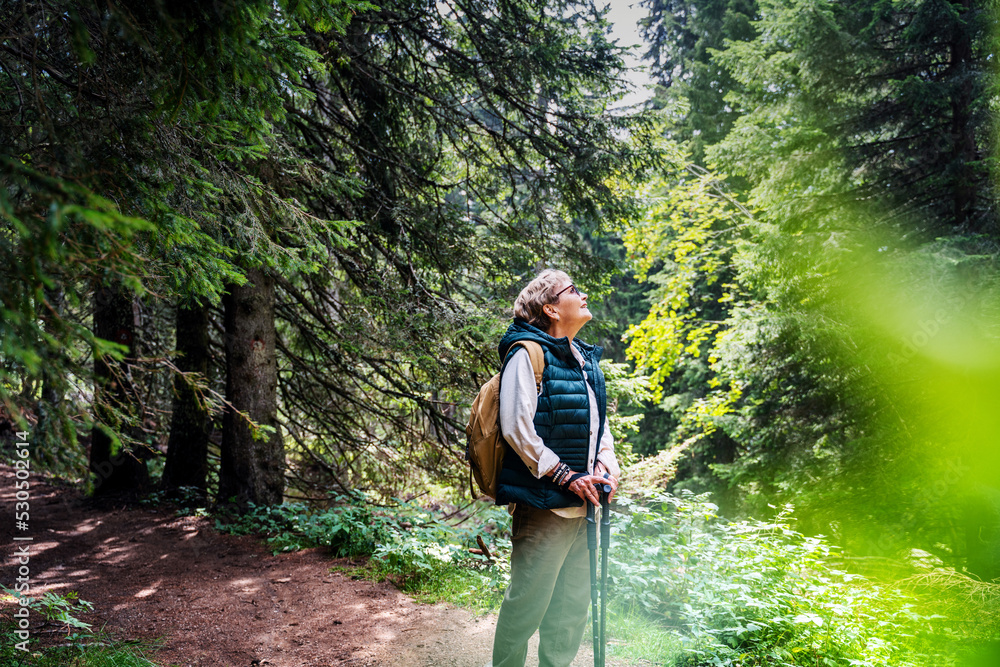Active happy mature senior woman walking in beautiful autumn forest