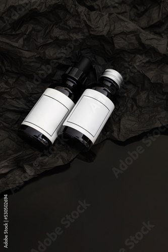 Two dropper bottles with whitea label on balck texture abackground. Moke up style for packaging photo