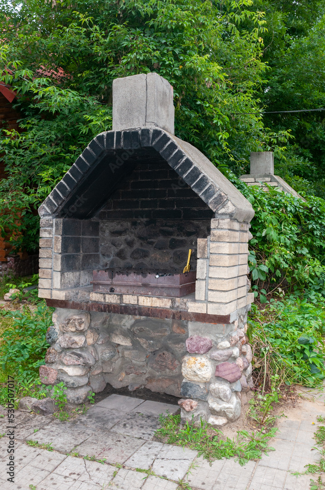 A stone garden oven for a grill or barbecue stands in the backyard