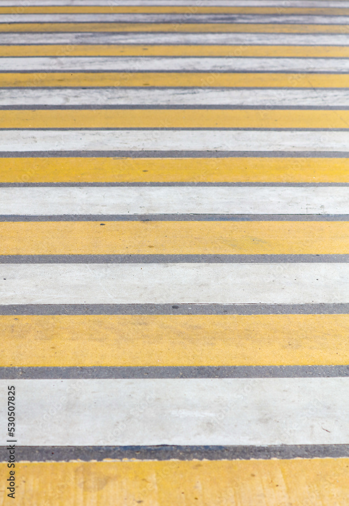 Yellow and white stripes on a pedestrian crossing.