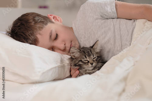 little asian boy with kitten sweetly sleep in bed. Child and cat. Kids and pets. Little kid with his animal. Toddler and kitty sleep.
