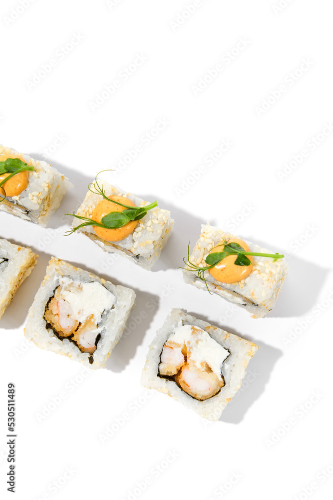 Maki sushi with sesame outside, tempura shrimp inside topped spicy sauce and microgreens. Spicy shrimp maki roll isolated on white background Trendy sushi roll with crispy prawn and hard shadows Maki sushi with sesame outside, tempura shrimp inside topped spicy sauce and microgreens. Spicy shrimp maki roll isolated on white background Trendy sushi roll with crispy prawn and hard shadows