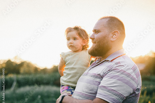 Father and daughter in the sunlight walking in the field