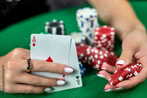 young beautiful lady croupier with artistic joker makeup on red background holding ace card