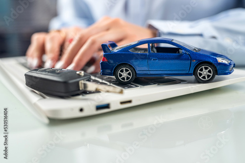 hands of a woman on a desk behind a keyboard with a small model car.