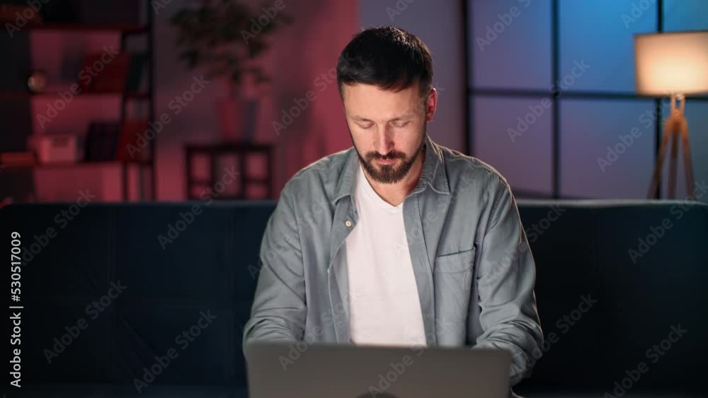 Modern bearded man working remotely on laptop chatting online browsing internet at evening home Modern bearded man working remotely on laptop chatting online browsing internet at evening home
