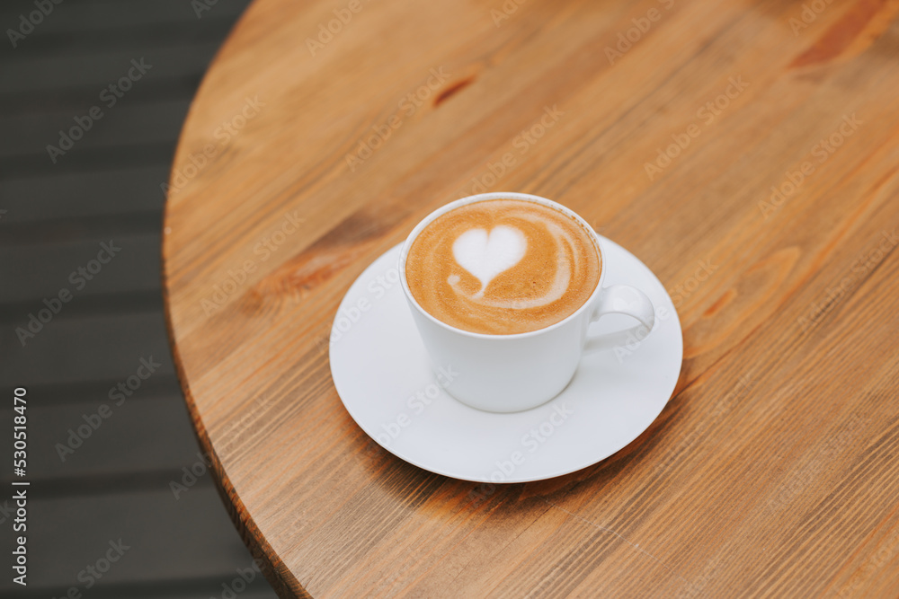 Double cappuccino with a beautiful foam and a heart in a white crook on the table. Beautiful coffee serving. Stylish aromatic coffee banner with space for text Double cappuccino with a beautiful foam and a heart in a white crook on the table. Beautiful coffee serving. Stylish aromatic coffee banner with space for text