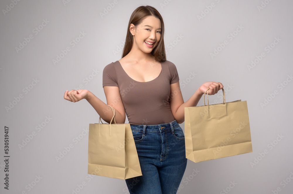 Young asian woman holding shopping bag over white background studio, shopping and finance concept. Young asian woman holding shopping bag over white background studio, shopping and finance concept.