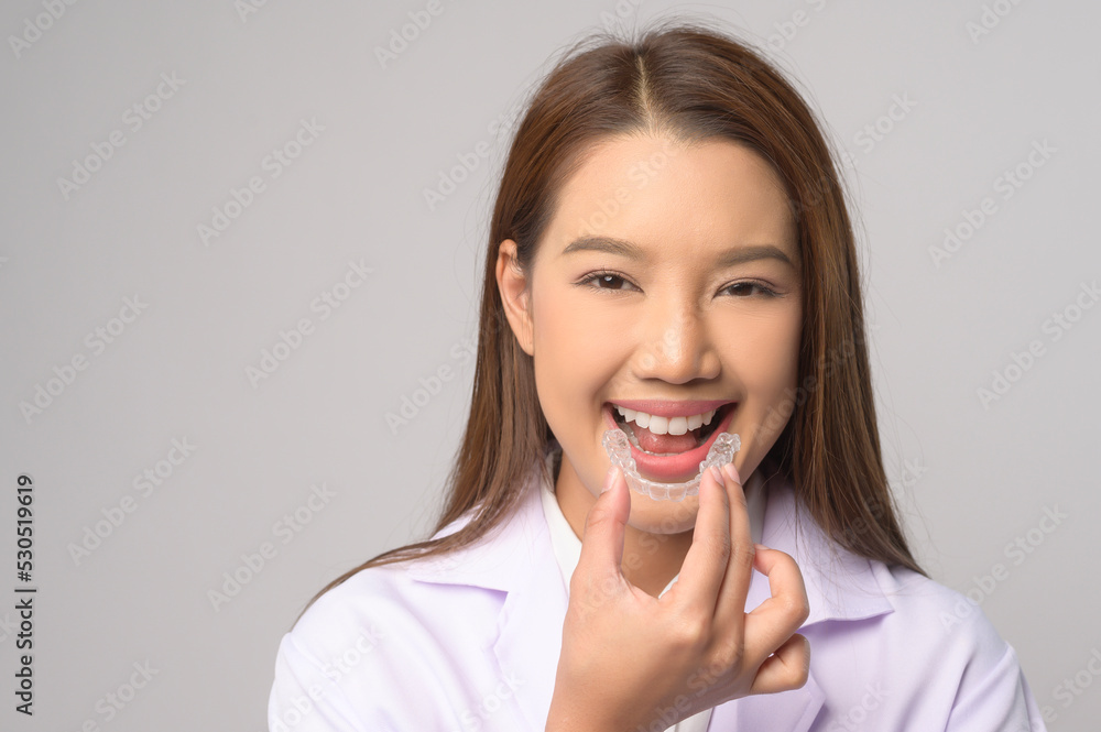 Young female dentist holding invisalign braces over white background studio, dental healthcare and Orthodontic concept.. Young female dentist holding invisalign braces over white background studio, dental healthcare and Orthodontic concept..