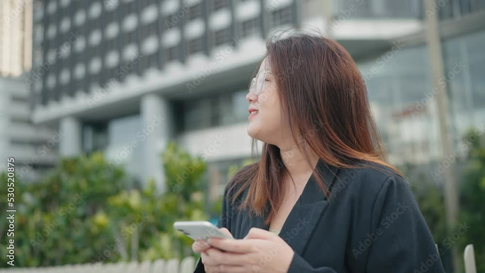 Smiling asian woman wearing glasses wakling in city street and using mobile phone typing text messages chatting online on social media. Smiling asian woman wearing glasses wakling in city street and using mobile phone typing text messages chatting online on social media.