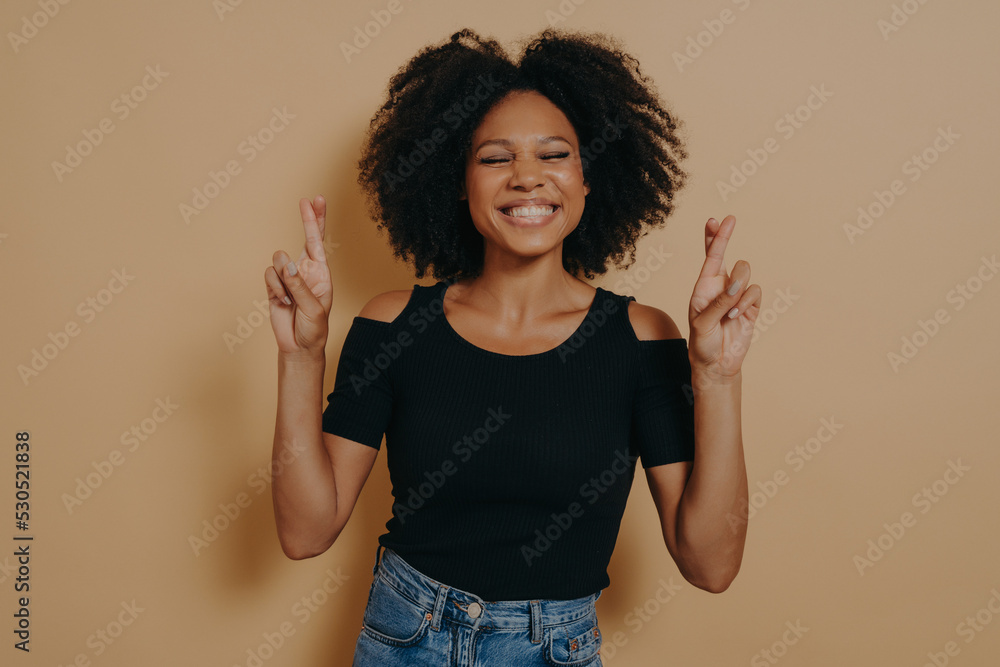 Cute lovely african american woman posing in casual clothes while gesturing fingers crossed sign Cute lovely african american woman posing in casual clothes while gesturing fingers crossed sign