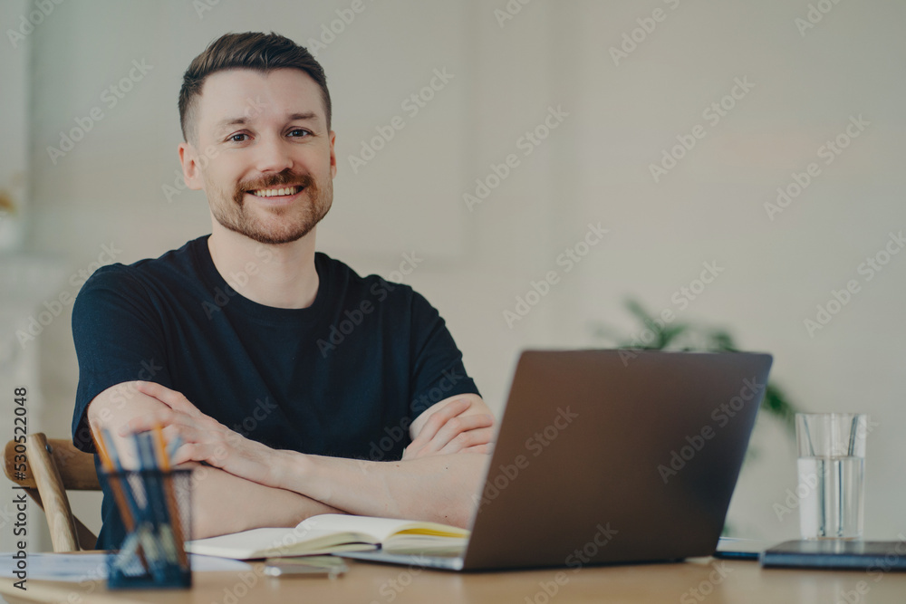 Portrait of happy businessman in casual wear sitting at his workplace in office or home Portrait of happy businessman in casual wear sitting at his workplace in office or home
