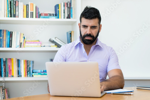 Serious hispanic businessman with beard working at computer