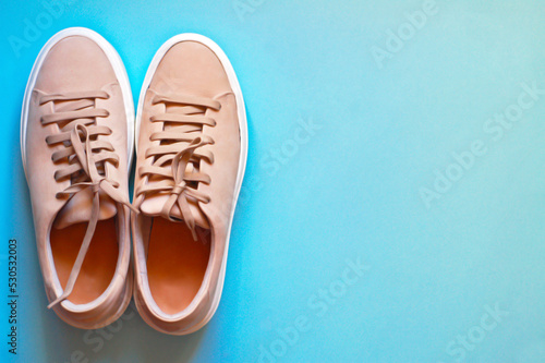 A pair of women's leather sneakers on a blue background. Shoes.