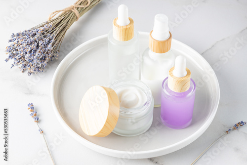 set of natural cosmetics with lavender extract - face cream, essential oil, serum on a tray. Organic herbal skin care