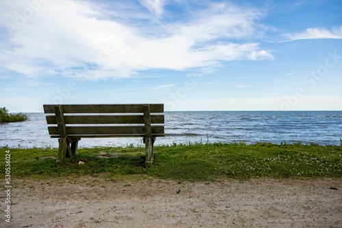 Fototapeta Naklejka Na Ścianę i Meble -  Wooden bench on the shore of a lake in Kingsville, Ontario