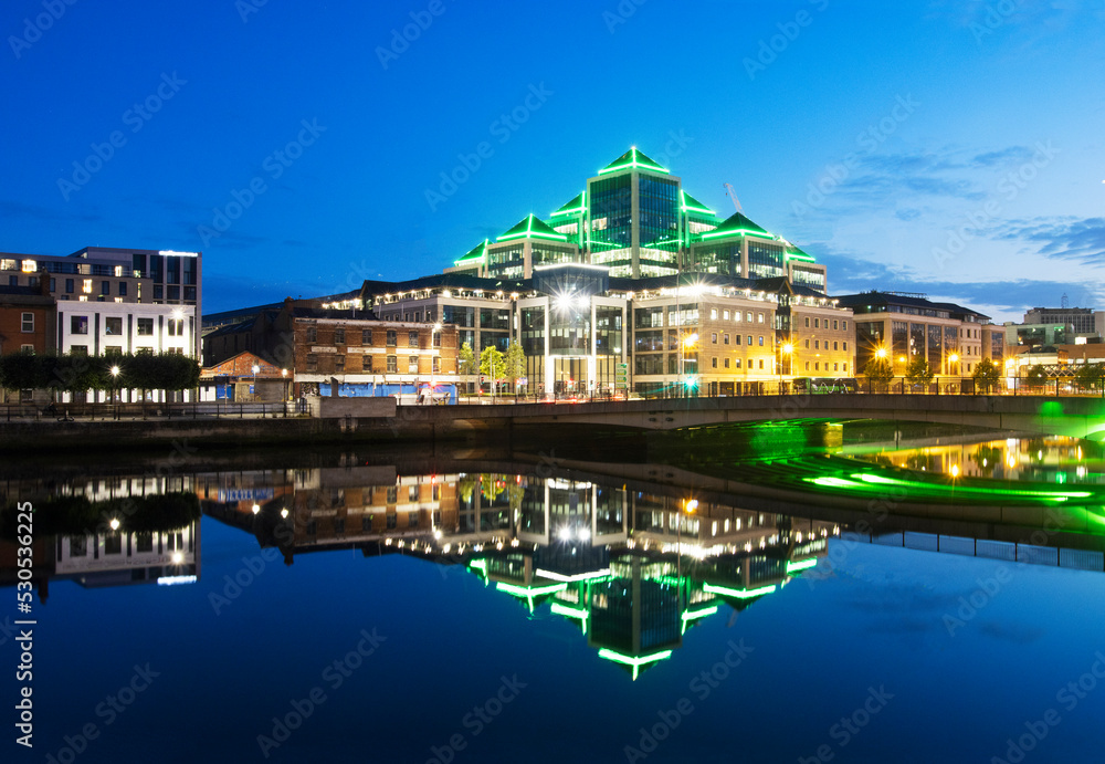 Skyline of the 'St George's Quay' also known as 'Canary Dwarf' reflected in the River Liffey illuminated at dusk