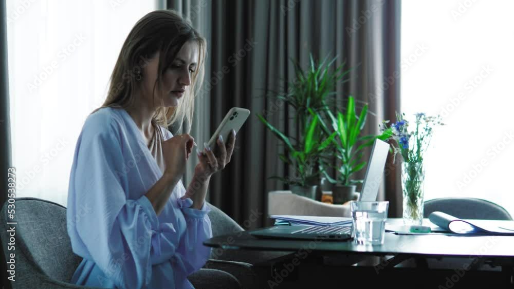 Businesswoman using mobile phone, texting a message. Female freelancer working from home with laptop and smartphone, modern technology Businesswoman using mobile phone, texting a message. Female freelancer working from home with laptop and smartphone, modern technology