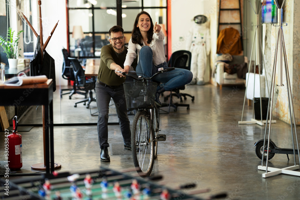 Colleagues in office. Businesswoman and businessman with bicycle. Two friends having fun together.. Colleagues in office. Businesswoman and businessman with bicycle. Two friends having fun together..