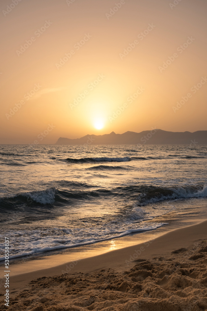 Sun sets behind the mountains in the background. Beautiful orange sunset. Relax, evening on vacation.