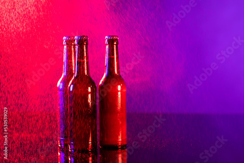Image of three brown beer bottles with crown caps, with copy space on red and purple background