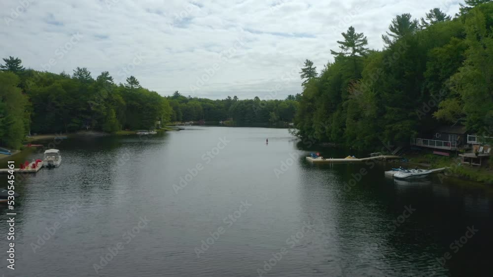 Aerial view passing a paddle-border on a river. Cloudy day in Muskoka, Ontario. Drone view. Aerial view passing a paddle-border on a river. Cloudy day in Muskoka, Ontario. Drone view.
