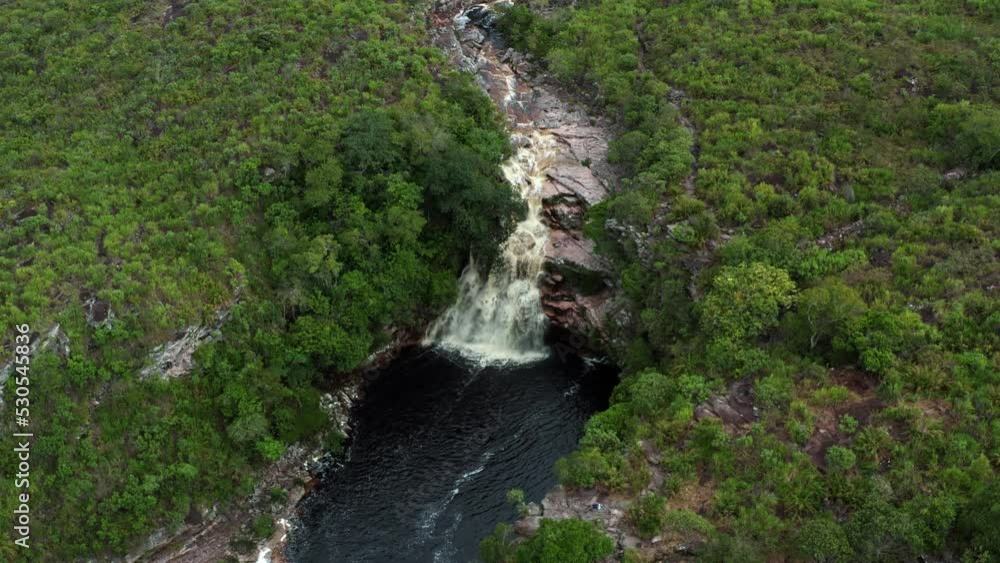 Aerial drone rotating shot of the stunning Devil's Pit waterfall surrounded by rocks and jungle foliage in the beautiful Chapada Diamantina National Park in Northeastern Brazil on an overcast day. Aerial drone rotating shot of the stunning Devil's Pit waterfall surrounded by rocks and jungle foliage in the beautiful Chapada Diamantina National Park in Northeastern Brazil on an overcast day.