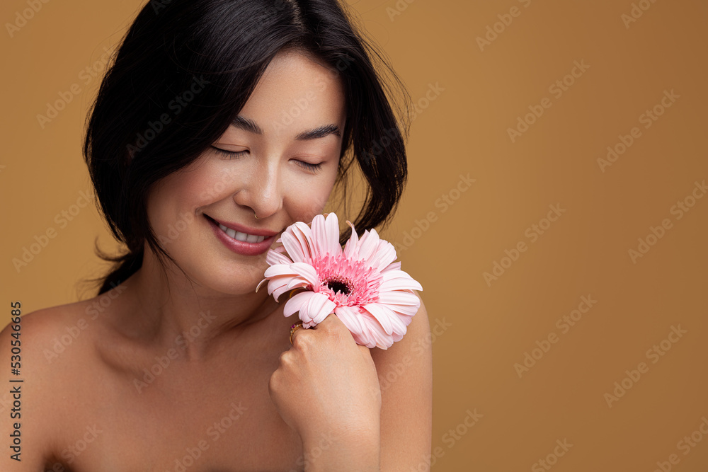 Asian woman touching face with flower