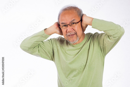 Deaf. Asian unhappy elder man Suffering from a loud sound ignoring someone studio shot isolated on yellow background, Portrait senior old man with glasses sad covering ears with fingers hands