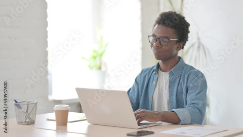 Young African Man Shaking Head in Rejection While using Laptop in Office