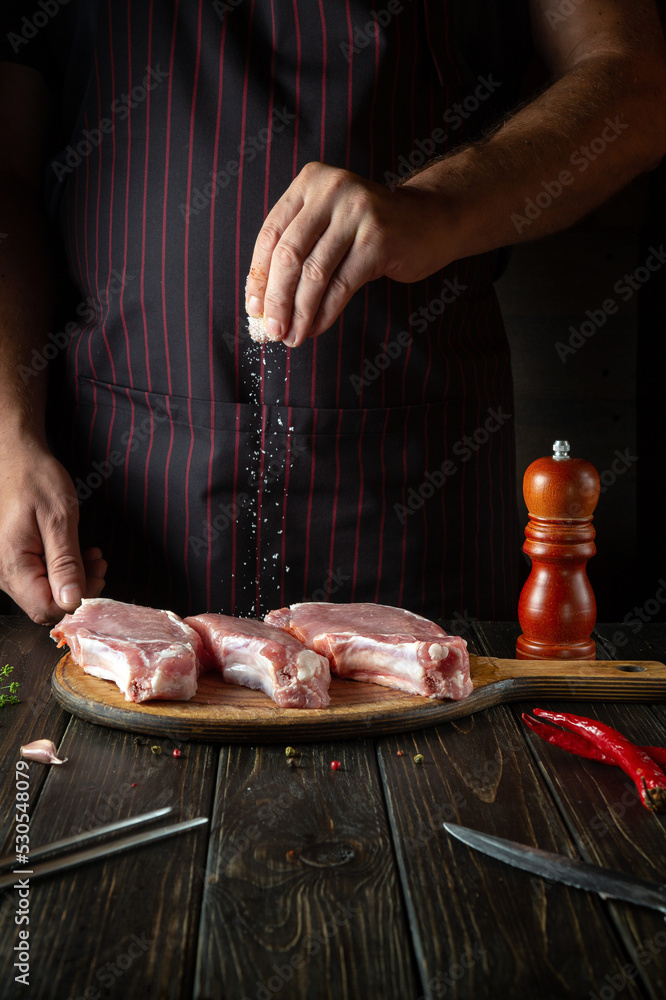 The chef sprinkles raw ribs with salt. The concept of cooking delicious food for the hotel or restaurant