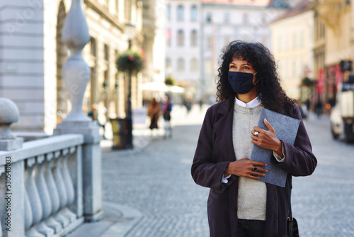 businesswoman outdoors with face mask holding folder documents