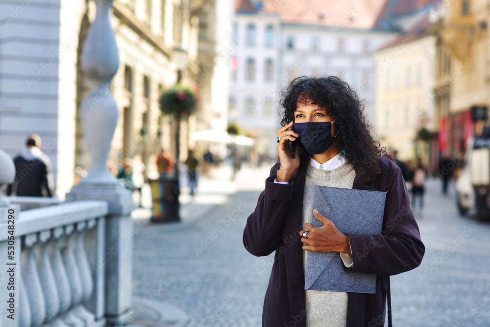 businesswoman outdoors with face mask talking on phone holding folder with documents businesswoman outdoors with face mask talking on phone holding folder with documents