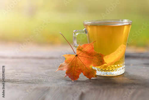 Autumn still life with a teacup with a slice of lemon on wooden boards and a blurred background in the background with a place to copy. Selective focus photo