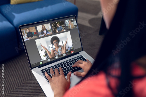 Biracial businesswoman making laptop video call with diverse colleagues on screen