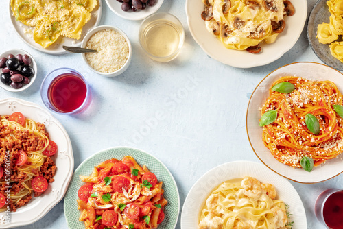 Italian pasta dishes forming a frame for copy space, overhead flat lay shot. Pastas with meat, vegetables, seafood, chicken and mushrooms, with ravioli, olives and wine