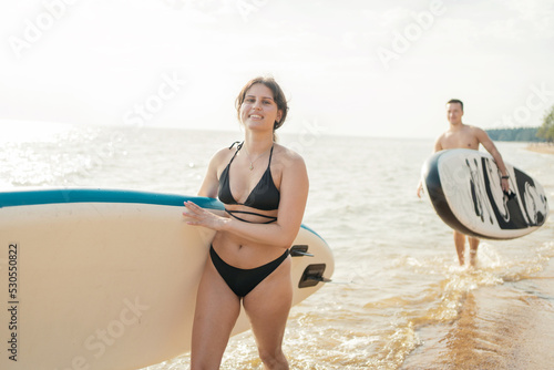 Friends man and woman go for a ride water sport sup board.